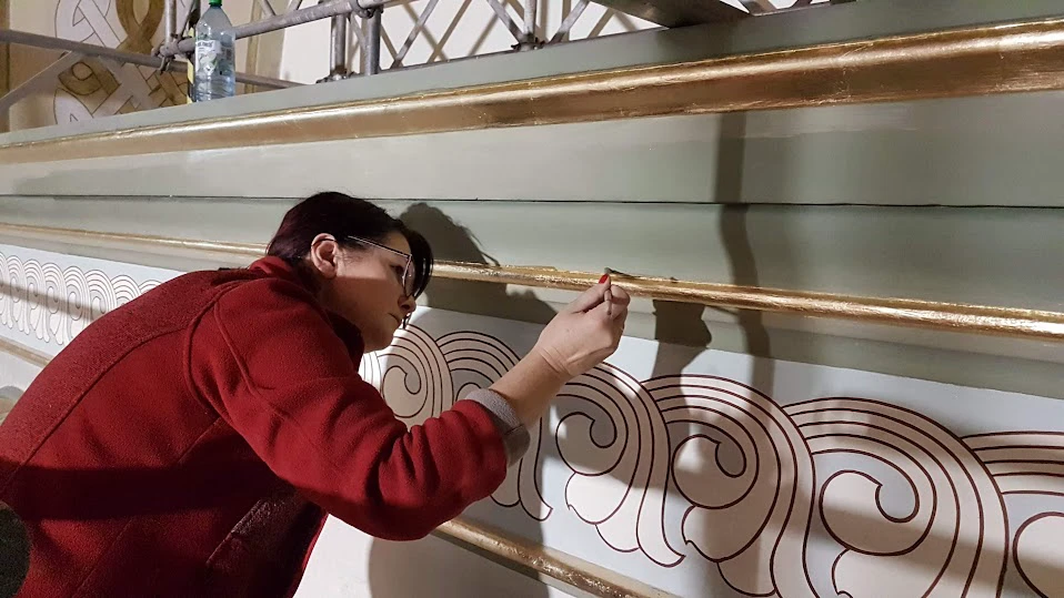 Złocenie ornamentalnego gzymsu wnętrza kościoła podczas prac konserwatorskich