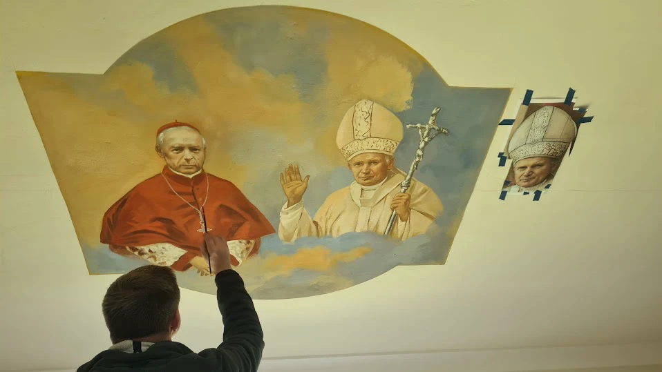Artysta malujący polichromię przedstawiającą postacie sakralne na sklepieniu kościoła
