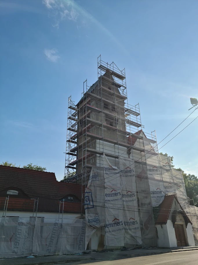 Remont kościoła z rusztowaniami wokół wieży i osłoną zabezpieczającą elewację