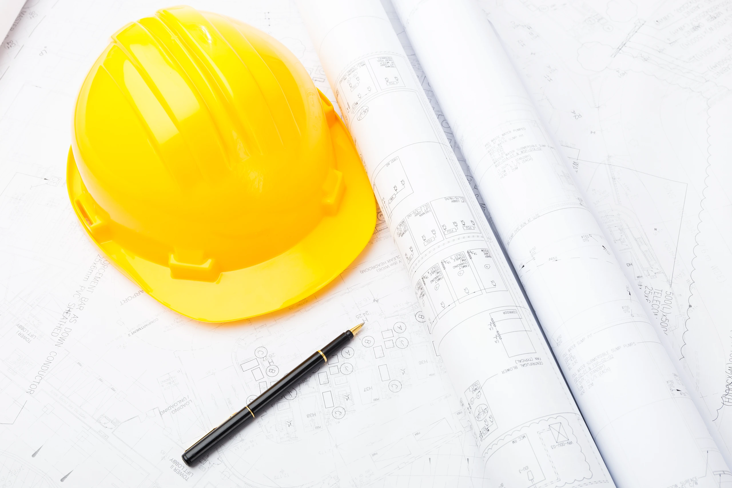 Żółty kask na planach budowlanych symbolizujący usługę Architekt
