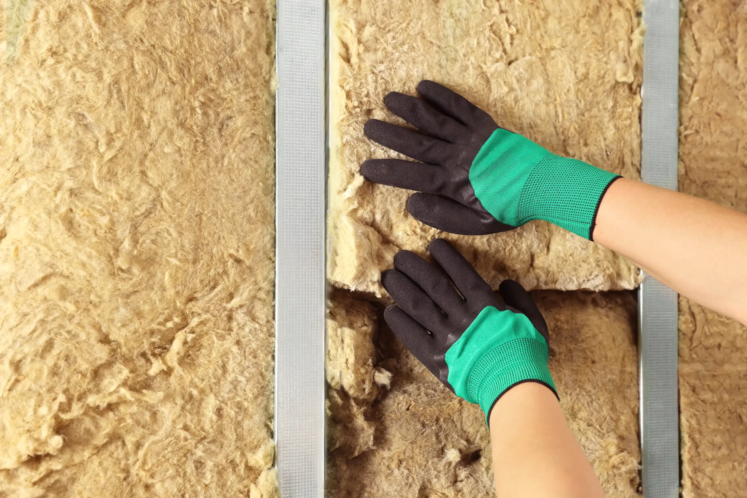 Montaż wełny mineralnej między metalowymi profilami – ocieplanie budynków