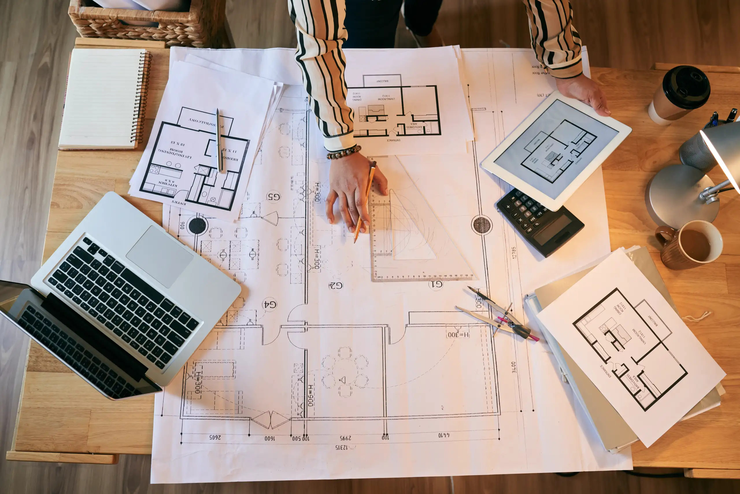 Architekt opracowujący plany budowlane na biurku z rzutami i narzędziami